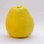 a yellow apple sitting on top of a white table