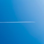 A plane leaves a white trail in a blue sky.