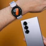 A person holding a smart watch on their wrist