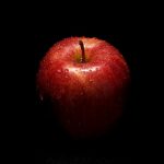 a red apple sitting on top of a black table
