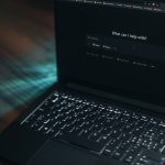A laptop displays a search bar asking how it can help.