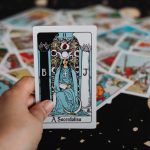 Hand holding a tarot card over a spread.