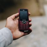 person holding black and red lg candybar phone