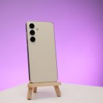 a cell phone on a wooden stand with a purple background