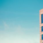 a tall pink building with blue windows against a blue sky