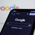 a close up of a cell phone with the google logo in the background
