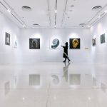 a person walking in a large room with art on the walls