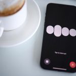 a cell phone sitting next to a cup of coffee