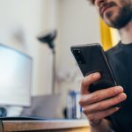 man in black crew neck shirt holding black iphone 5
