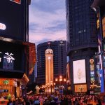 A crowd of people walking down a street next to tall buildings