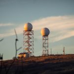 Two radar domes on towers on a hill.