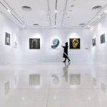 a person walking in a large room with art on the walls