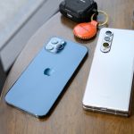 two cell phones sitting on top of a wooden table