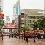 A group of people walking down a street next to tall buildings
