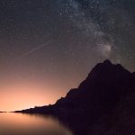 silhouette of mountain beside the body of water at night time