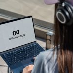 Person using laptop with ai integration logo displayed.