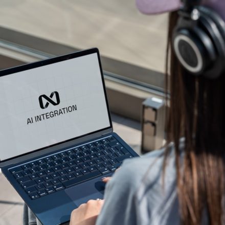 Person using laptop with ai integration logo displayed.