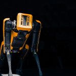 a yellow and black robot standing in the dark