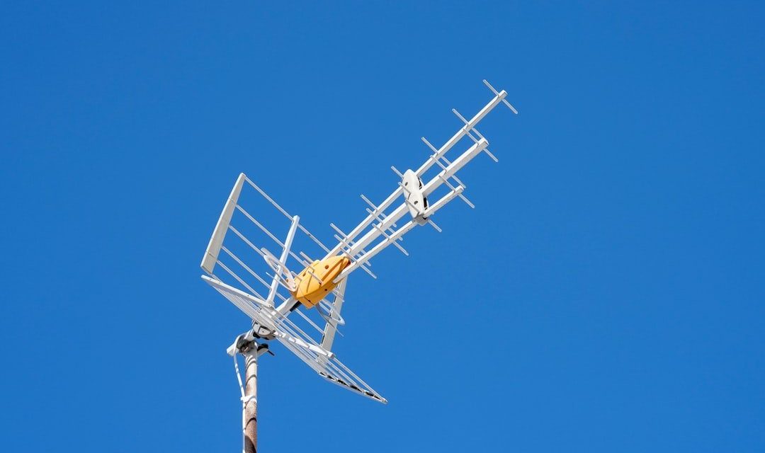 A white television antenna against a blue sky