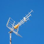 A white television antenna against a blue sky