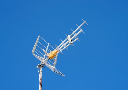 A white television antenna against a blue sky