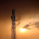 the sun is setting behind a tall tower