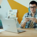 Man playing video game on phone at desk.
