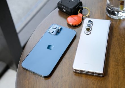two cell phones sitting on top of a wooden table
