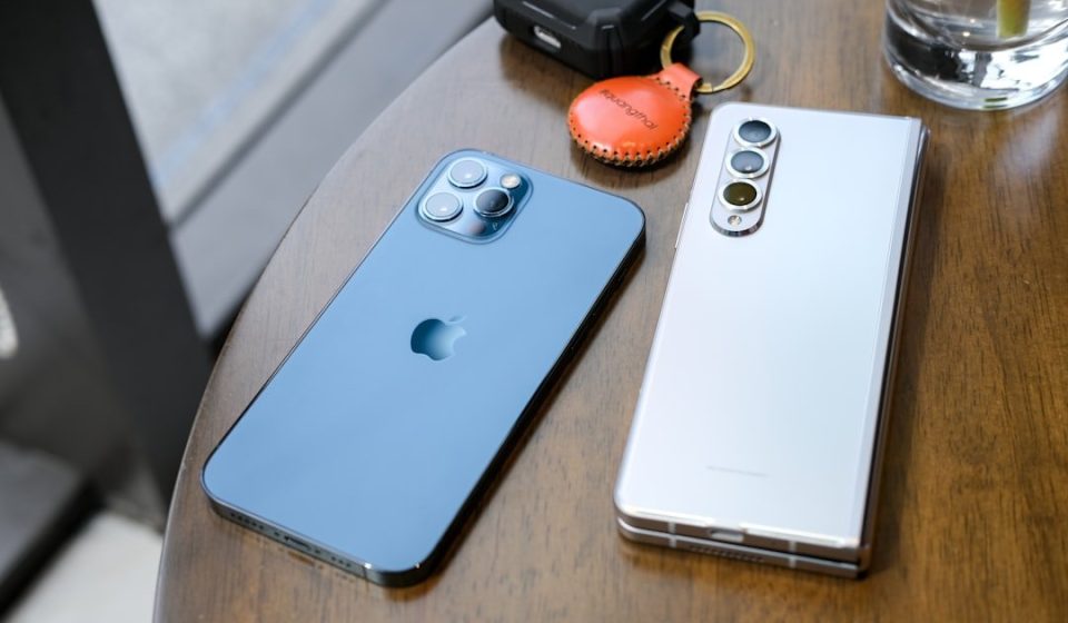 two cell phones sitting on top of a wooden table