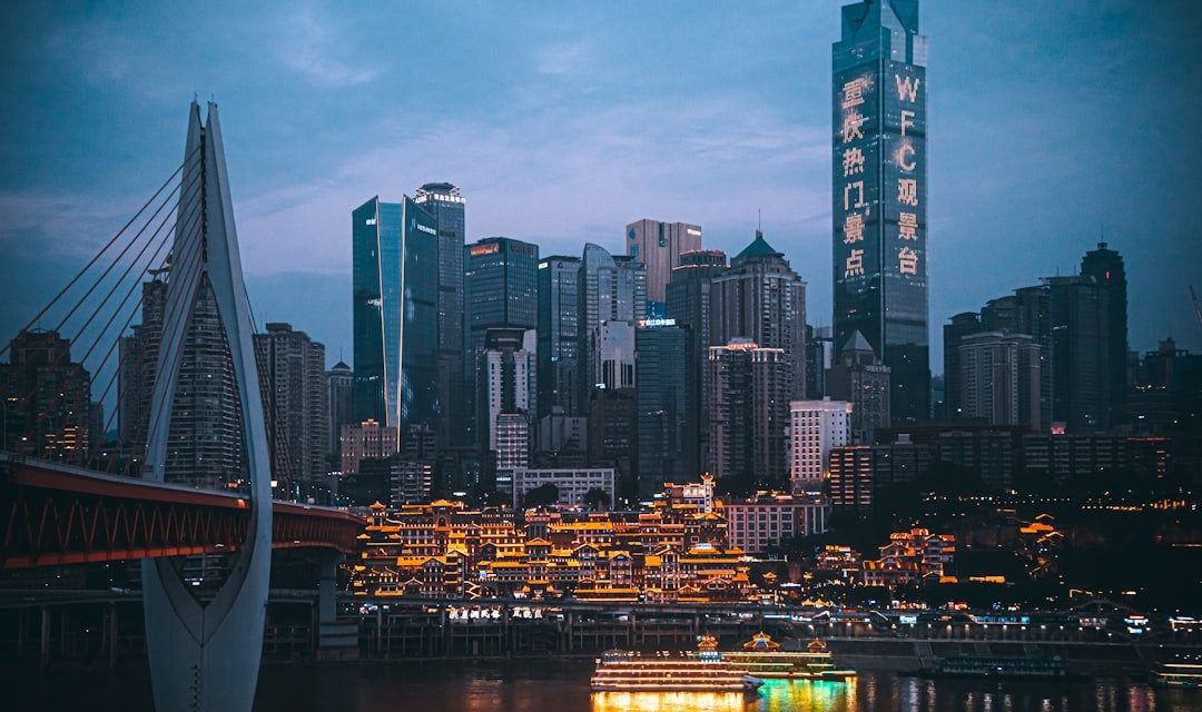 Illuminated cityscape at dusk with bridge and river.