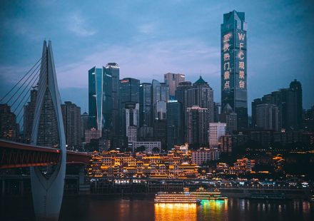 Illuminated cityscape at dusk with bridge and river.