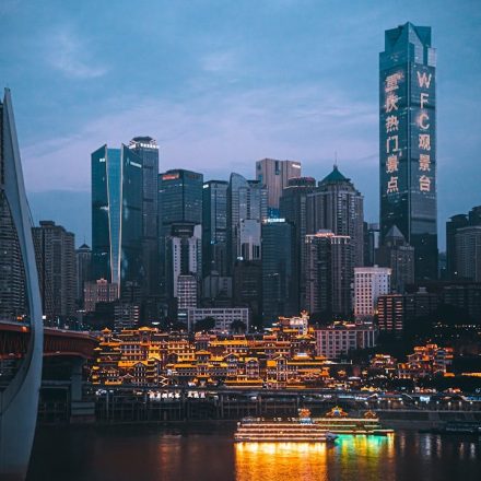 Illuminated cityscape at dusk with bridge and river.