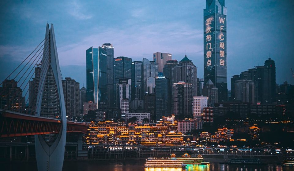 Illuminated cityscape at dusk with bridge and river.