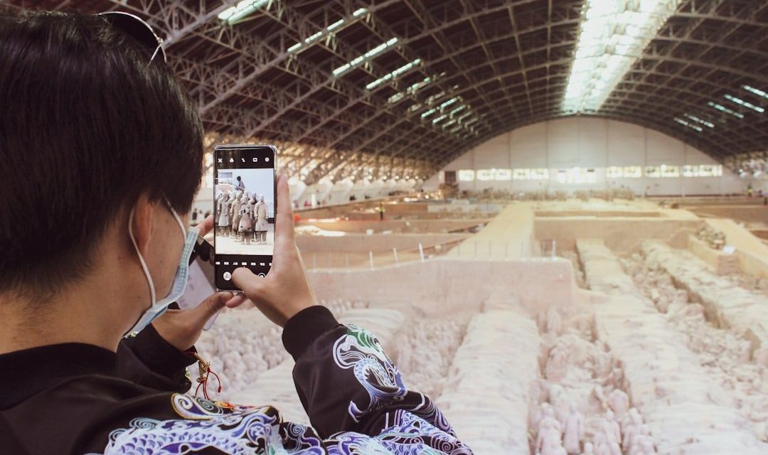 woman in black and white floral dress taking photo of a train station