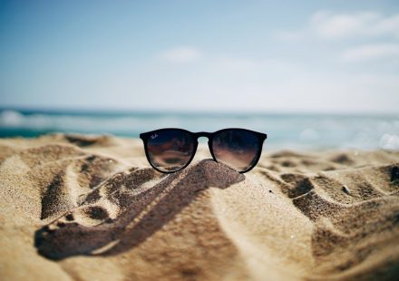 black Ray-Ban Wayfarer sunglasses on beach sand