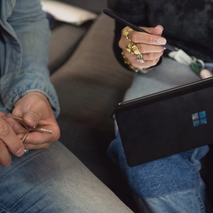 person in blue denim jeans holding Surface device
