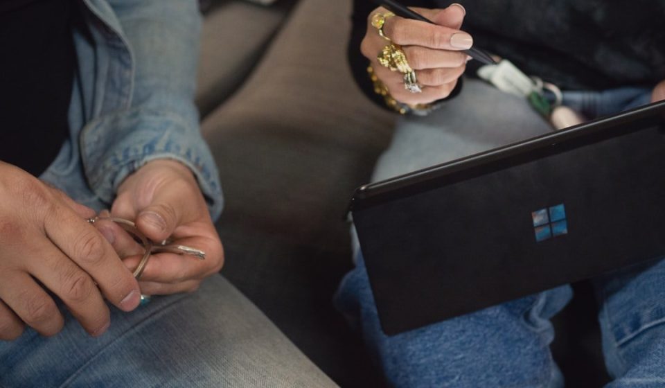person in blue denim jeans holding Surface device