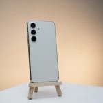 a white cell phone sitting on top of a wooden stand