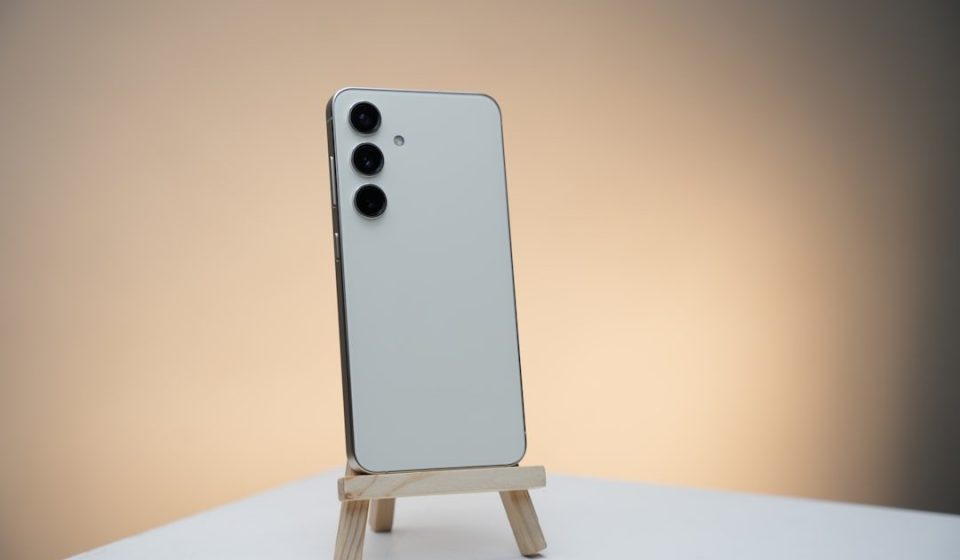 a white cell phone sitting on top of a wooden stand