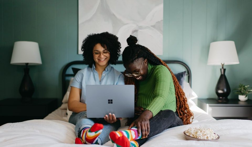 a woman sitting on a bed using a laptop